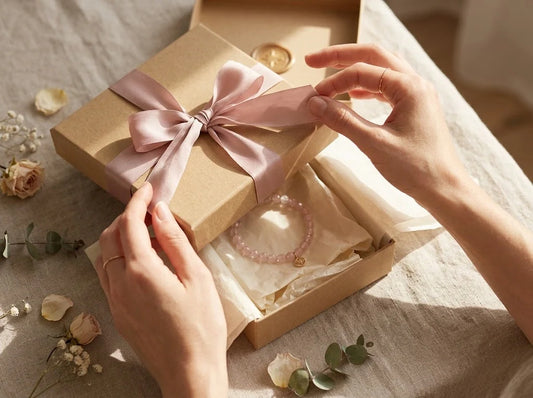 A close-up of a woman's hands tying a ribbon on a beautiful gift box, perfect as a thoughtful birthday gift idea for women.