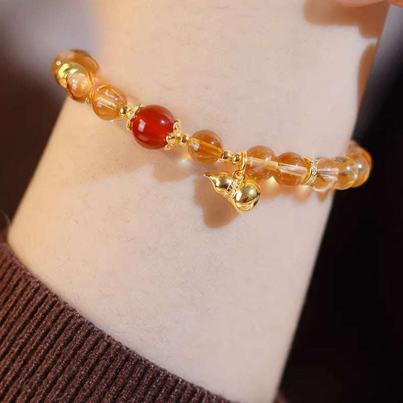 Close-up look of genuine citrine stones and a protective carnelian gourd charm by AURA LITH gemstone jewelry.