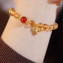 Close-up look of genuine citrine stones and a protective carnelian gourd charm by AURA LITH gemstone jewelry.