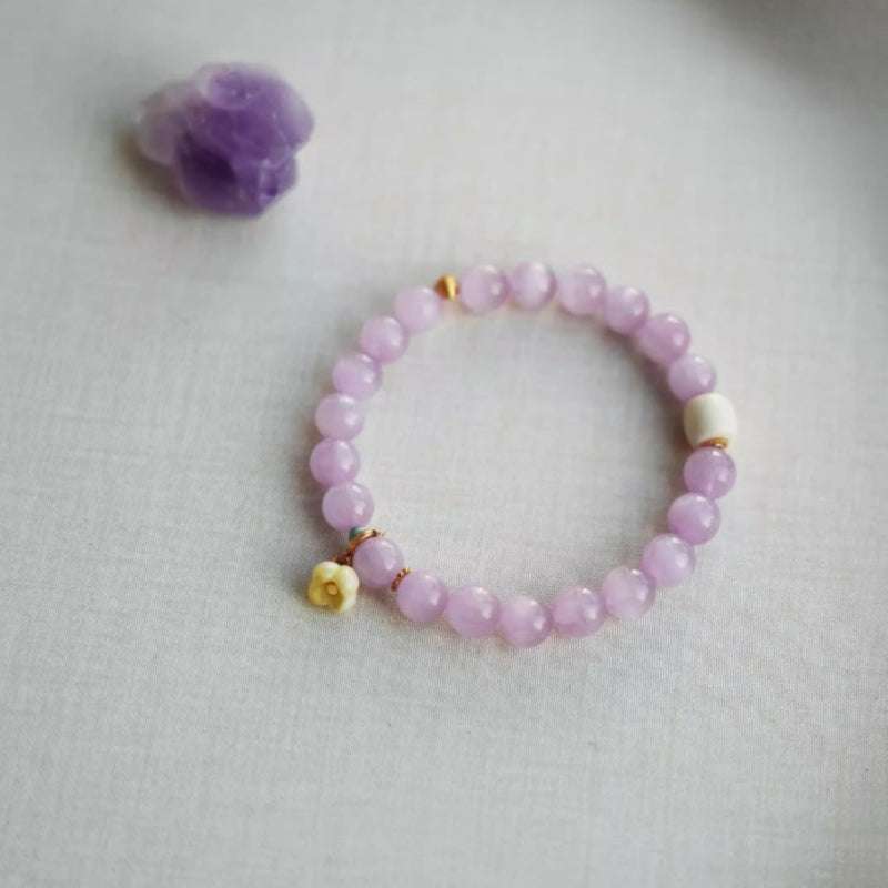 Close-up look of genuine 7A grade lavender kunzite beads and intricate floral charms from AURA LITH cosmic jewelry.