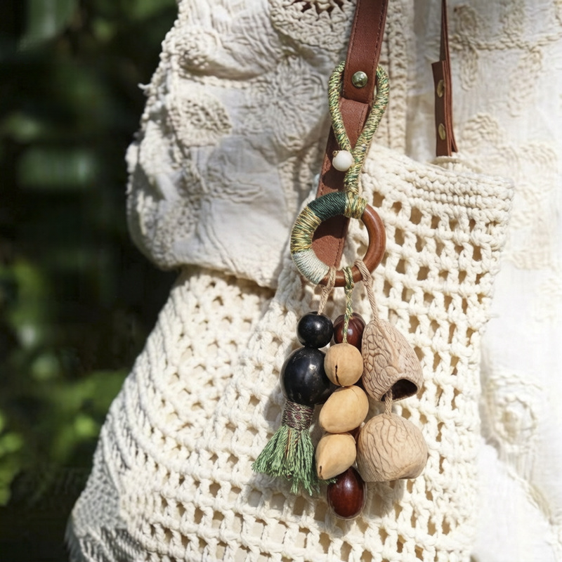 Handcrafted natural seed pod wind chime displayed as a boho-style accessory on a woven bag.